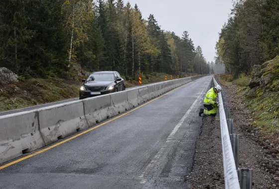 Vägarbetare vid räcket, bakom en betongbarriär